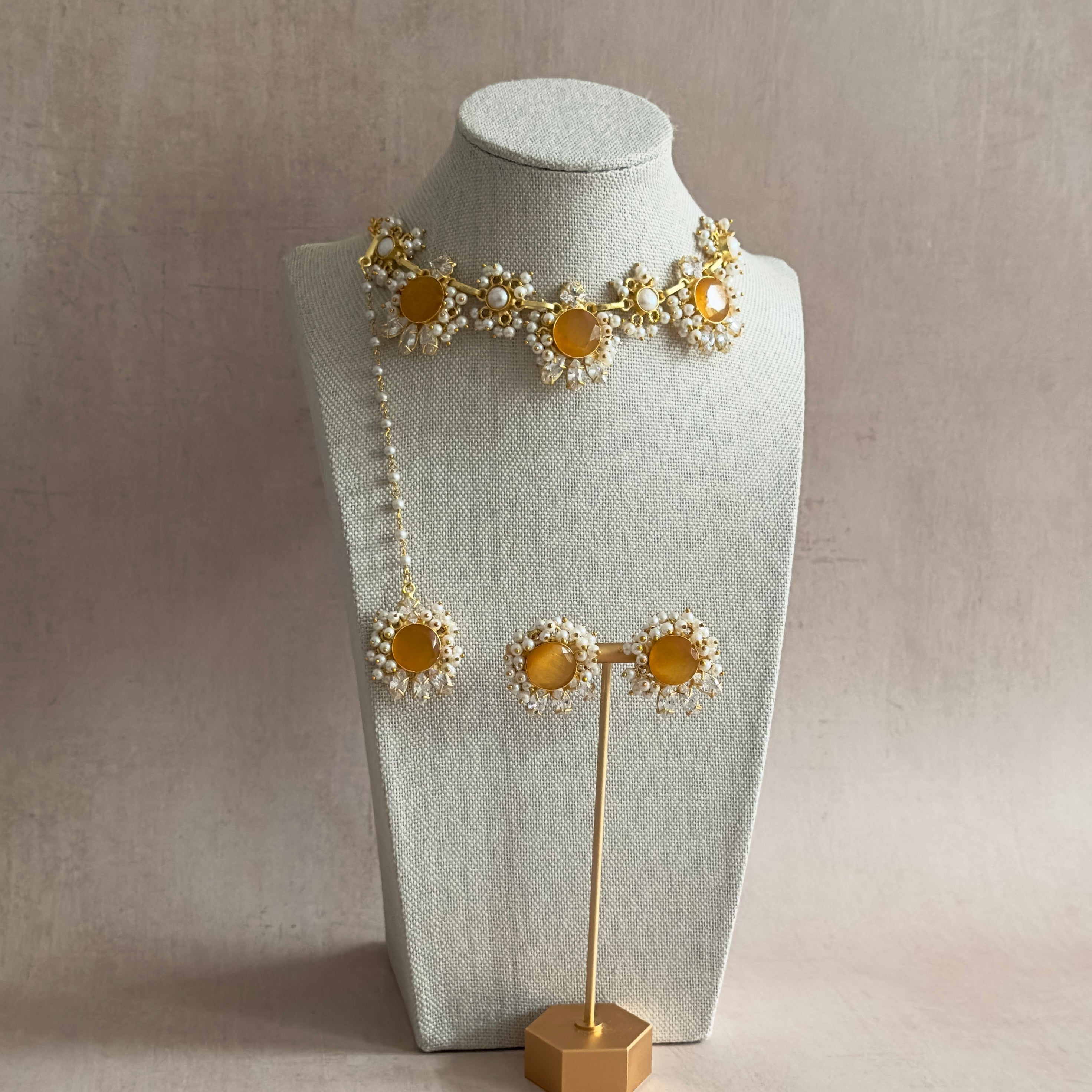 Indulge in the timeless elegance of the Aroz Amber Necklace Set. The stunning amber stones, complemented by the unique shape and texture of freshwater pearls, add a touch of luxury to any outfit. With added sparkle from cubic zirconia, this set is complete with matching earrings and tikka for a truly mesmerizing look.