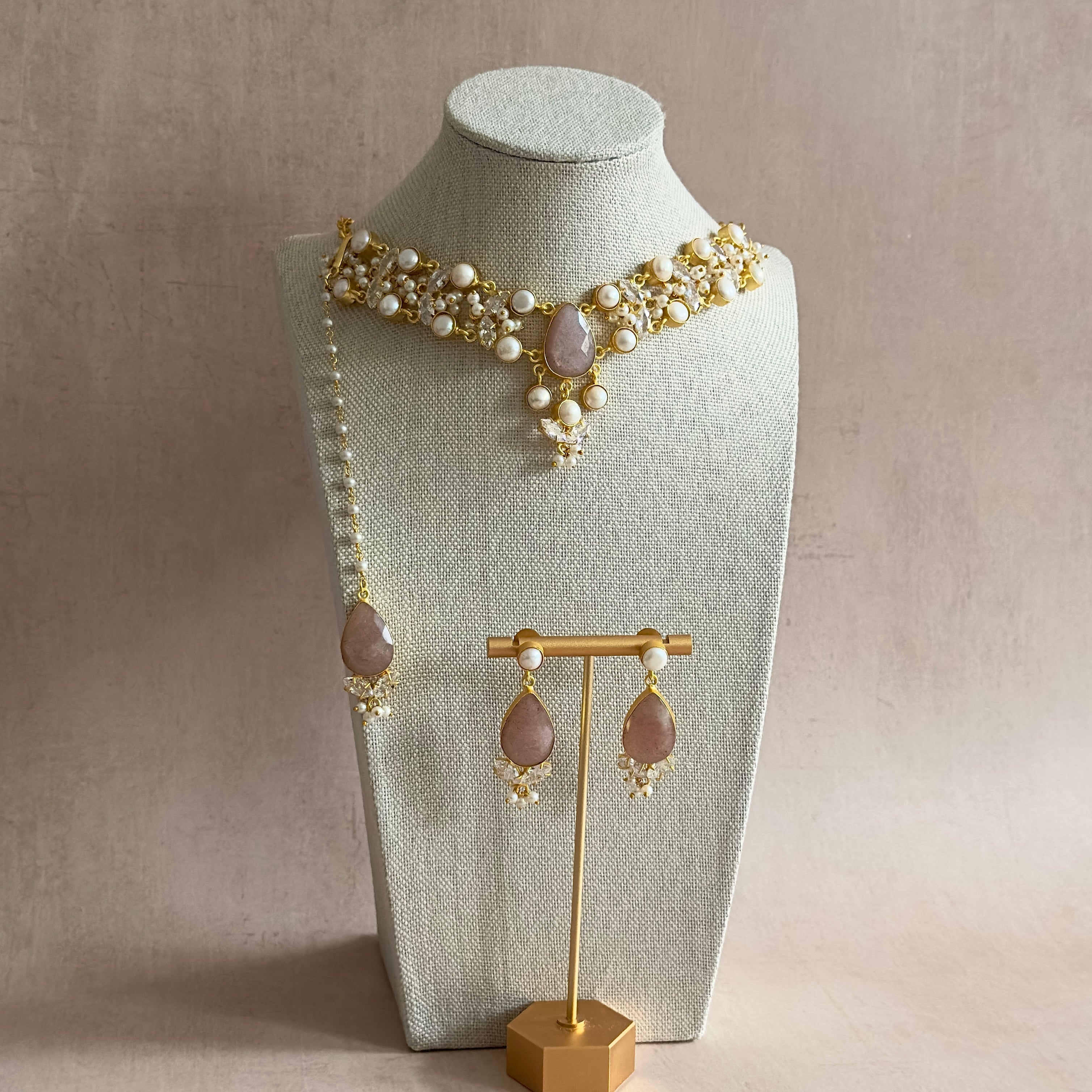 Unleash your inner glamour with our Ari Mink Pearl Choker Set. The gorgeous mink and pearl tones complement each other perfectly, while the cubic zirconia adds a touch of sparkle. The adjustable chain ensures a perfect fit, complete with matching earrings and tikka for a stunning look. Elevate your style and be the center of attention with this exquisite set!