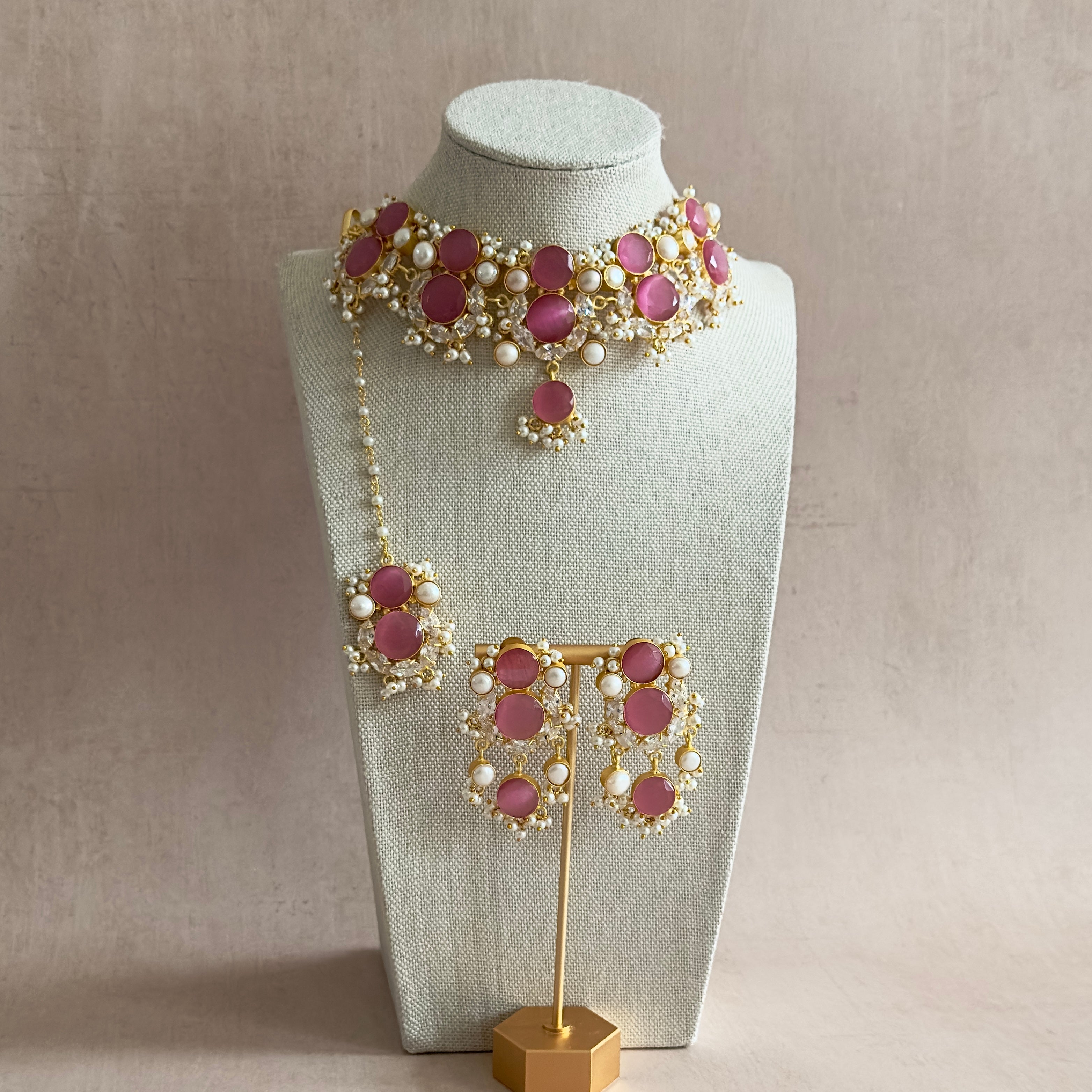Elevate your style with our Havana Pink Choker Set! This stunning statement set features pink stones, sparkling CZ crystals, and delicate pearl accents. Complete with matching earrings and tikka, this set will add an elegant touch to any outfit. Stand out and make a statement with this must-have accessory!