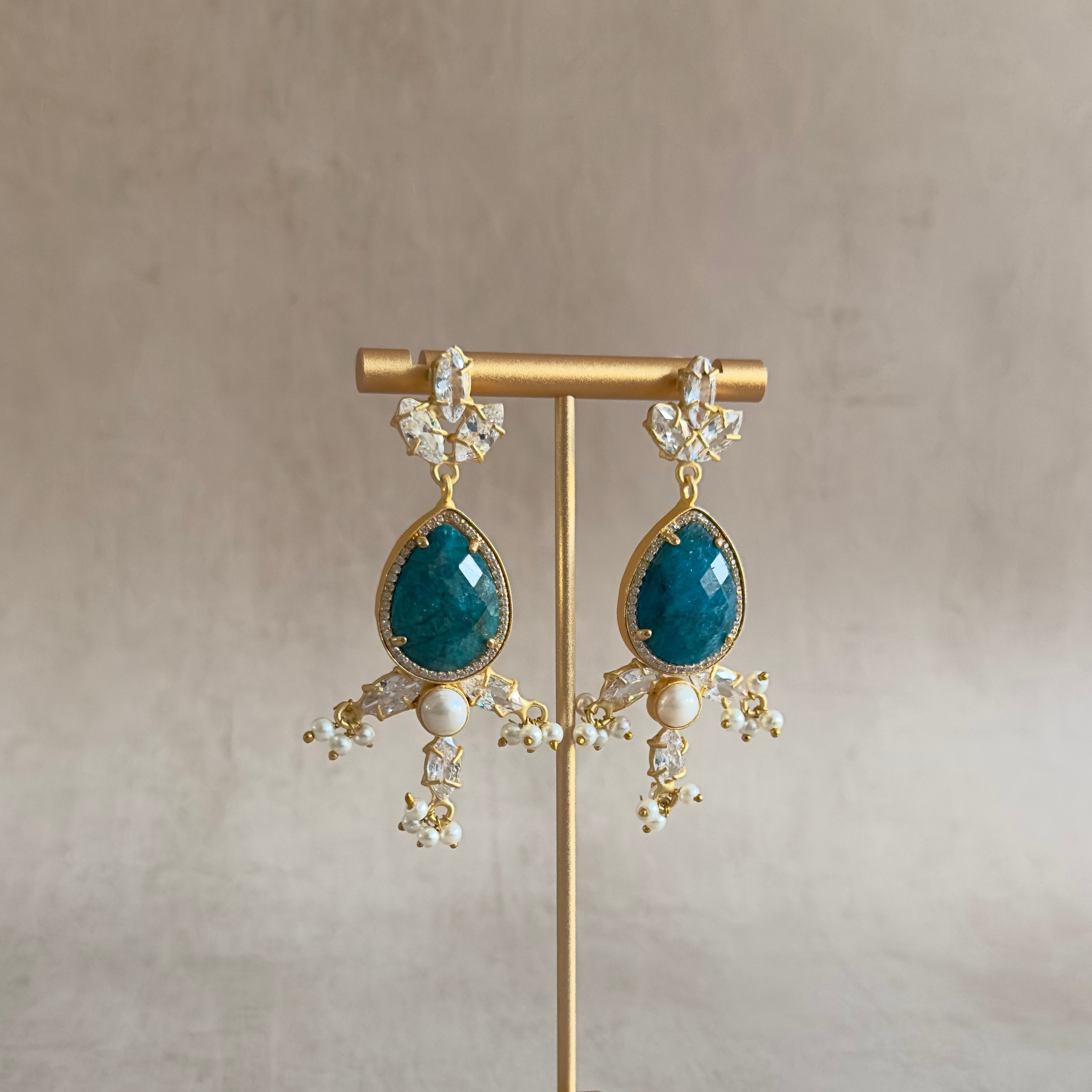 Introducing the Simone Teal Crystal Earrings, a stunning combination of teal gemstones, sparkling cz crystals, and delicate freshwater pearls. Elevate any outfit with these elegant and versatile earrings, perfect for any occasion. Add a touch of sophistication and sparkle to your accessory collection today!