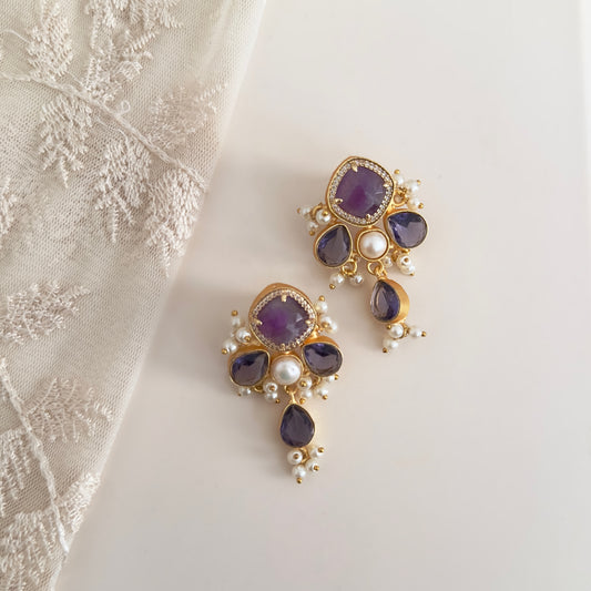 "Add a touch of elegance to your outfit with the Lara Purple Drop Earrings. Featuring stunning purple stones and delicate pearl accents, these earrings are perfect for any occasion. Elevate your style and make a statement with these beautiful earrings."<br>Earring drop 4.5cm