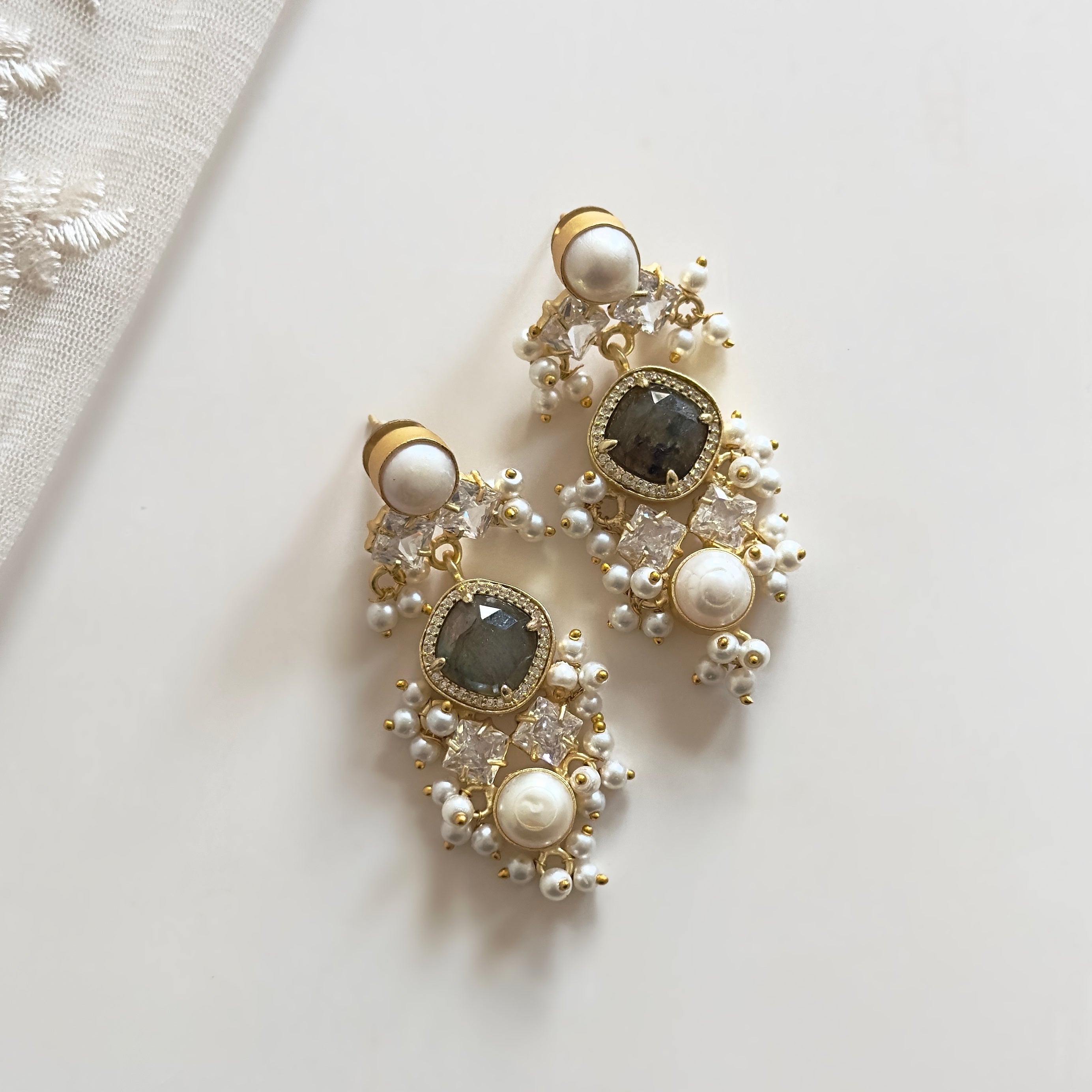 Enhance your look with the Sana Crystal Drop Earrings. Made with luscious labradorite stones, pearls, and CZ crystals, these earrings exude elegance and sophistication. The iridescent hues of the labradorite stones and the shimmering accents of the pearls and CZ crystals will add a touch of glamour to any outfit.