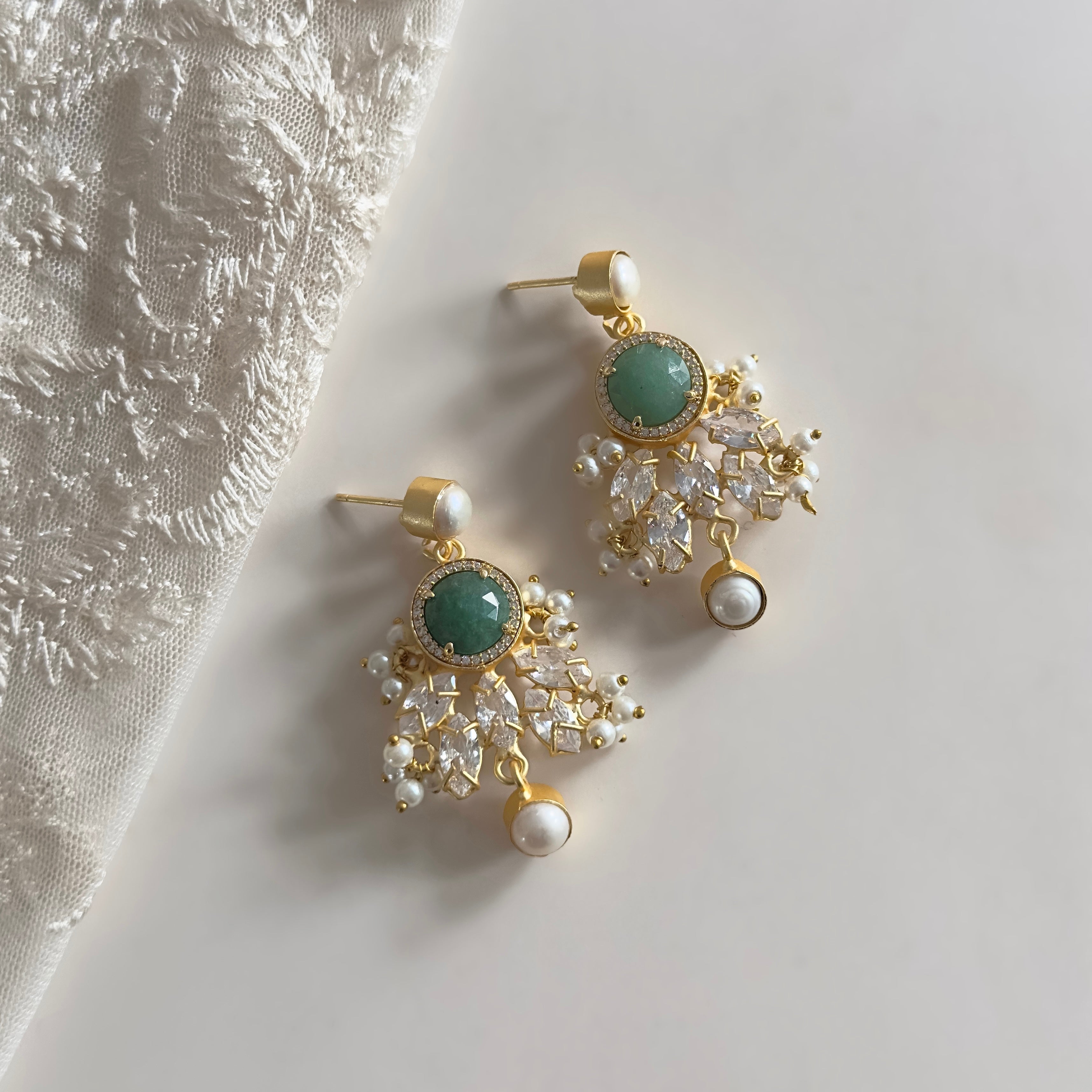 These exquisite Jade Crystal Drop Earrings feature a stunning green aventurine gemstone, complemented by sparkling cz crystals and delicate pearl accents. Indulge in luxury with these handcrafted earrings that add a touch of elegance to any outfit.