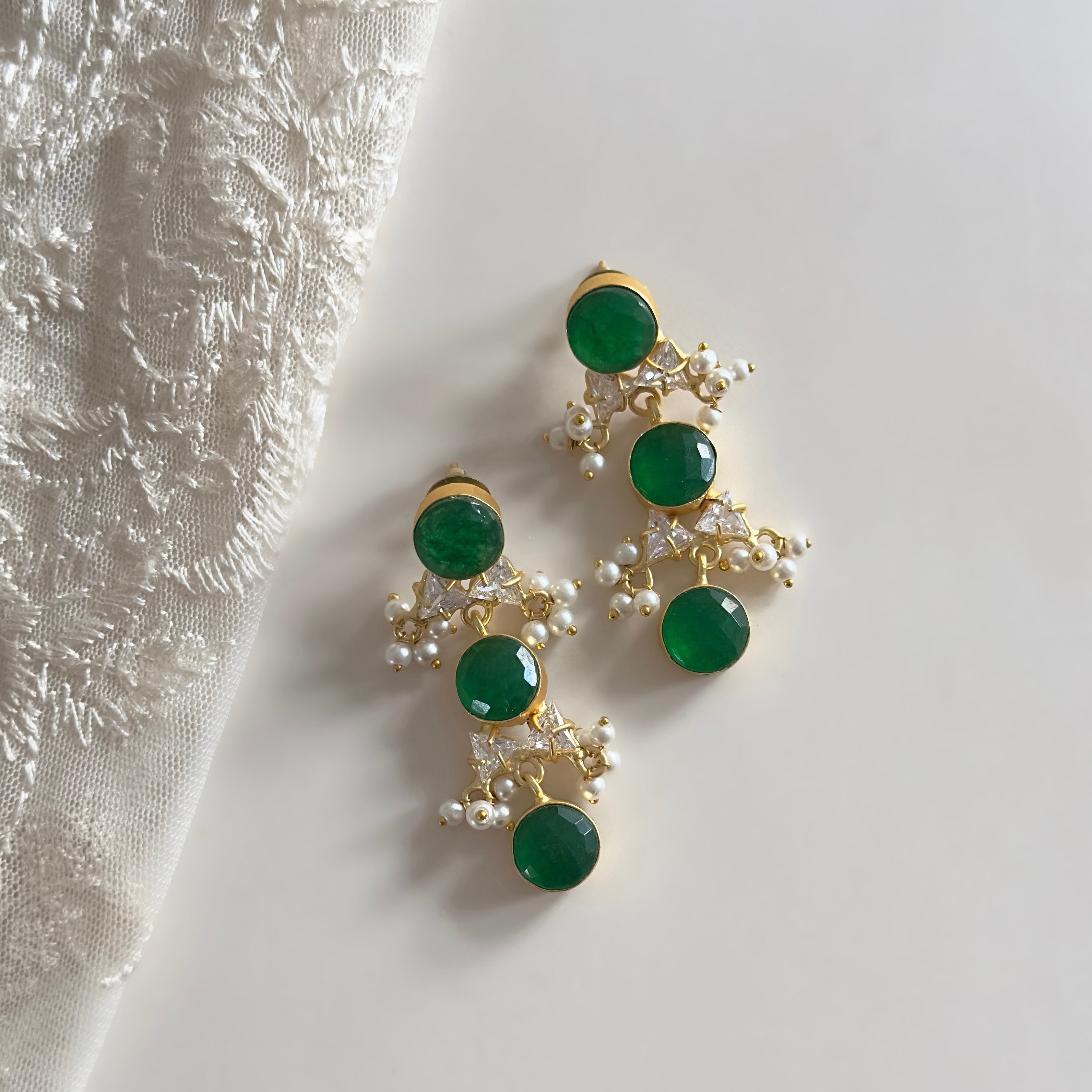 Elevate your look with these Green Crystal Drop Earrings, adorned with sparkling cz crystals and stunning green stones. Add a touch of sophistication and elegance to any ensemble.