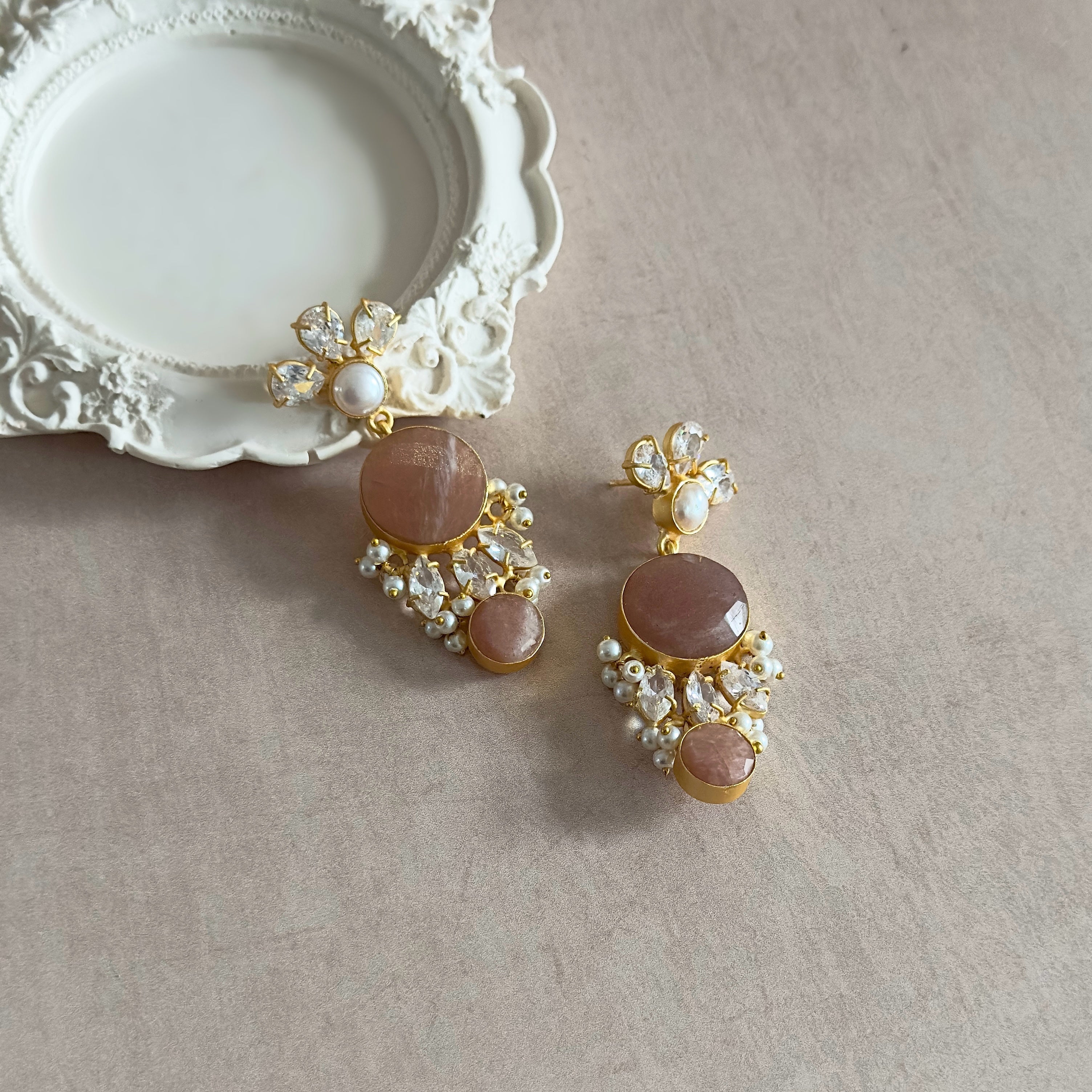 Indulge in these Peachy Crystal Drop Earrings and elevate your style with their stunning peachy hues! Adorned with sparkling cz crystals and delicate pearl accents, these earrings are perfect for adding a touch of elegance and glamour to any outfit. A must-have for any fashion lover!