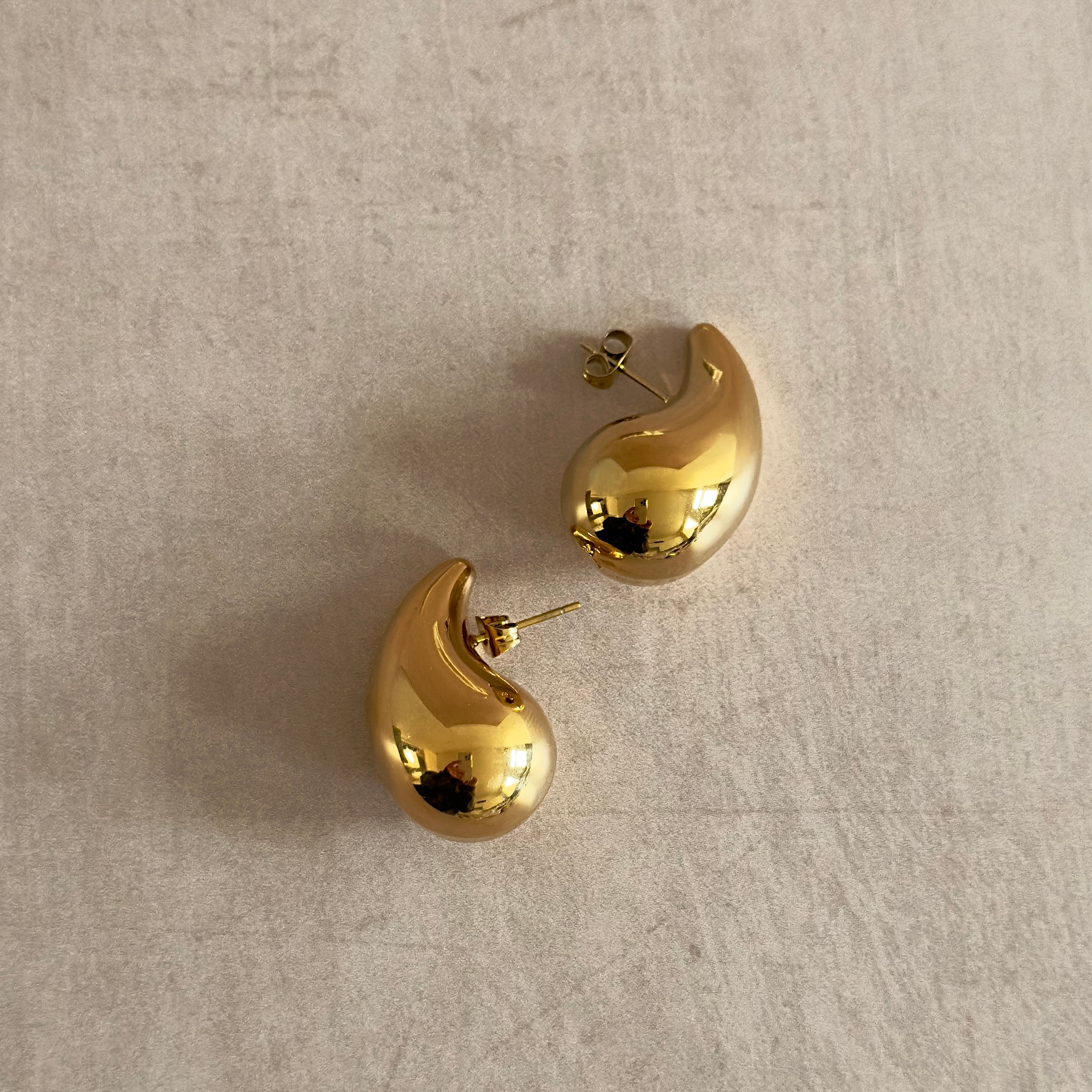 Introducing Lola Teardrop Earrings: A timeless teardrop design, these 18k gold plated earrings are perfect for adding a touch of luxury to any outfit. Their elegant brushed finish gives them a regal, sophisticated look that will turn heads and elevate any ensemble.
