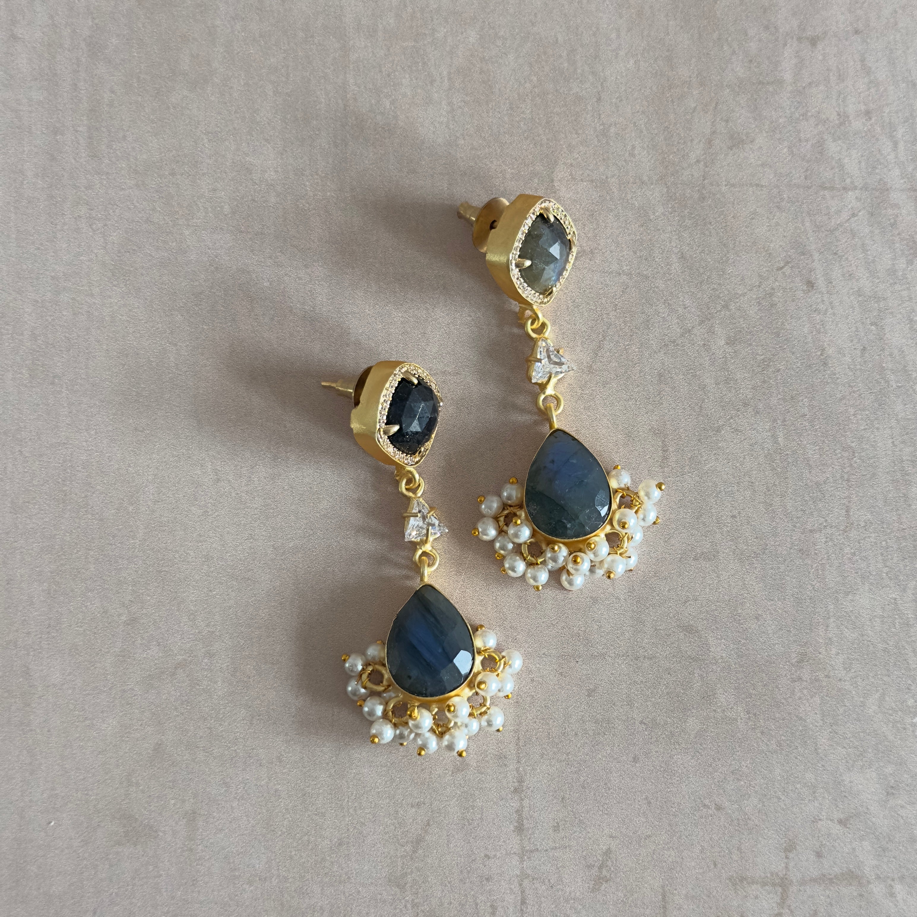 Elevate any look with these Sarah Crystal Drop Earrings, featuring lustrous labradorite stones and a dazzling cubic zirconia crystal. Add a touch of elegance and sparkle to any outfit.