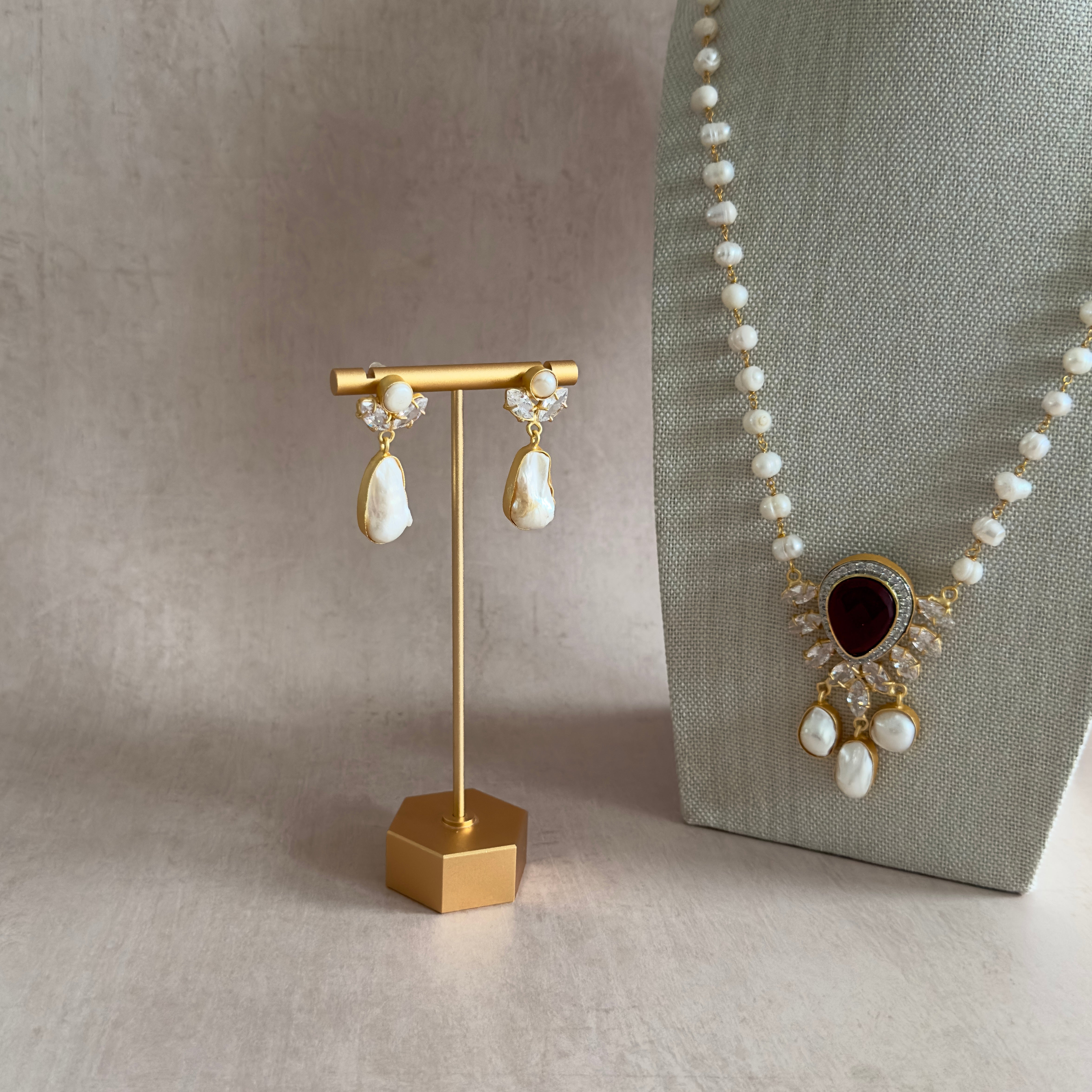 This elegant Mala Set features a stunning combination of ruby stones and freshwater pearls, accented with crystal zirconias. The set also includes a pair of baroque pearl and crystal earrings. Enhance your beauty and energy with this glamorous accessory.