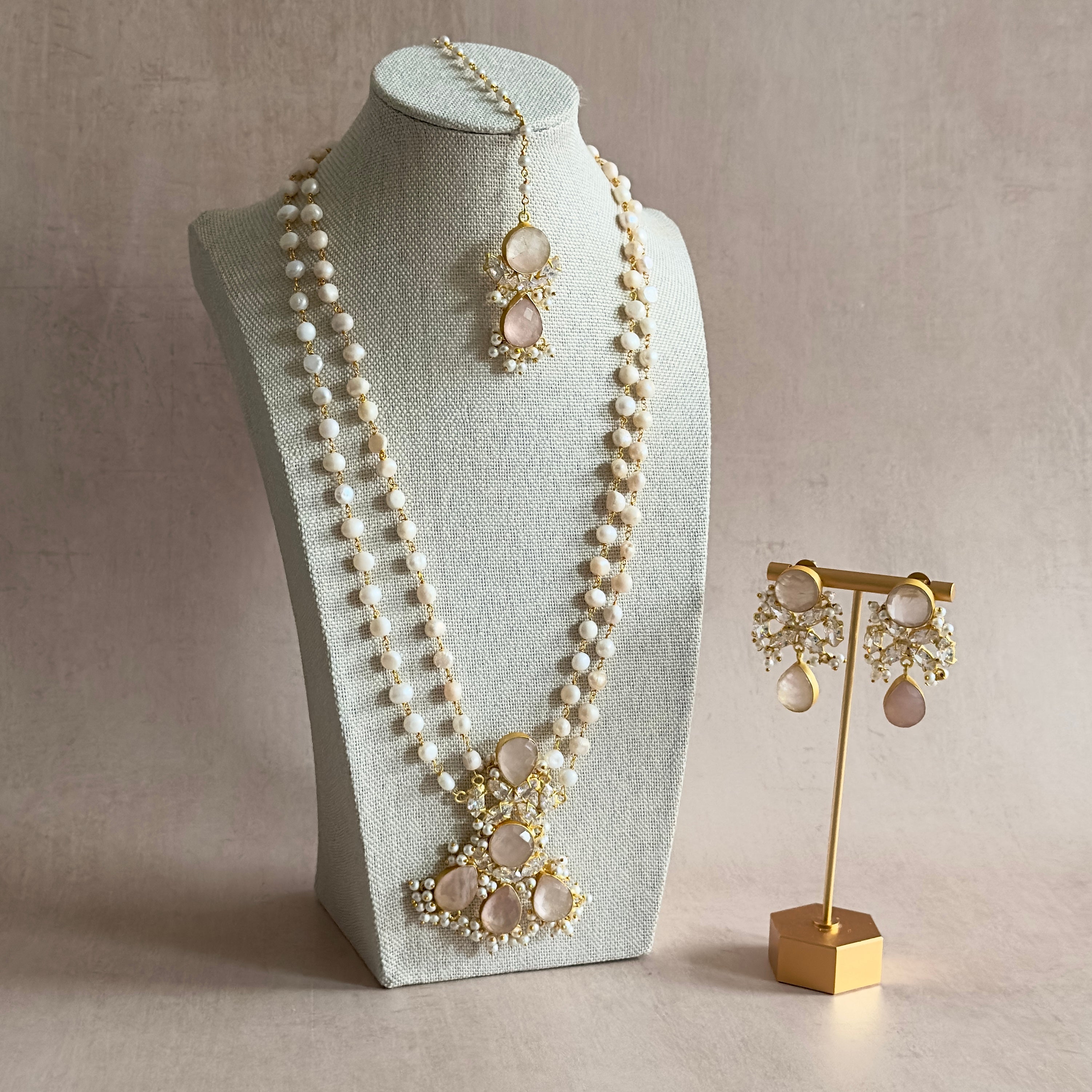 Indulge in the charming Romona Rose Mala Set! This stunning 3 piece set features&nbsp; natural rose quartz stones, complemented by a double pearl necklace and sparkling cz crystals. Complete with matching earrings and tikka, this set is sure to add a touch of elegance and beauty to any outfit.