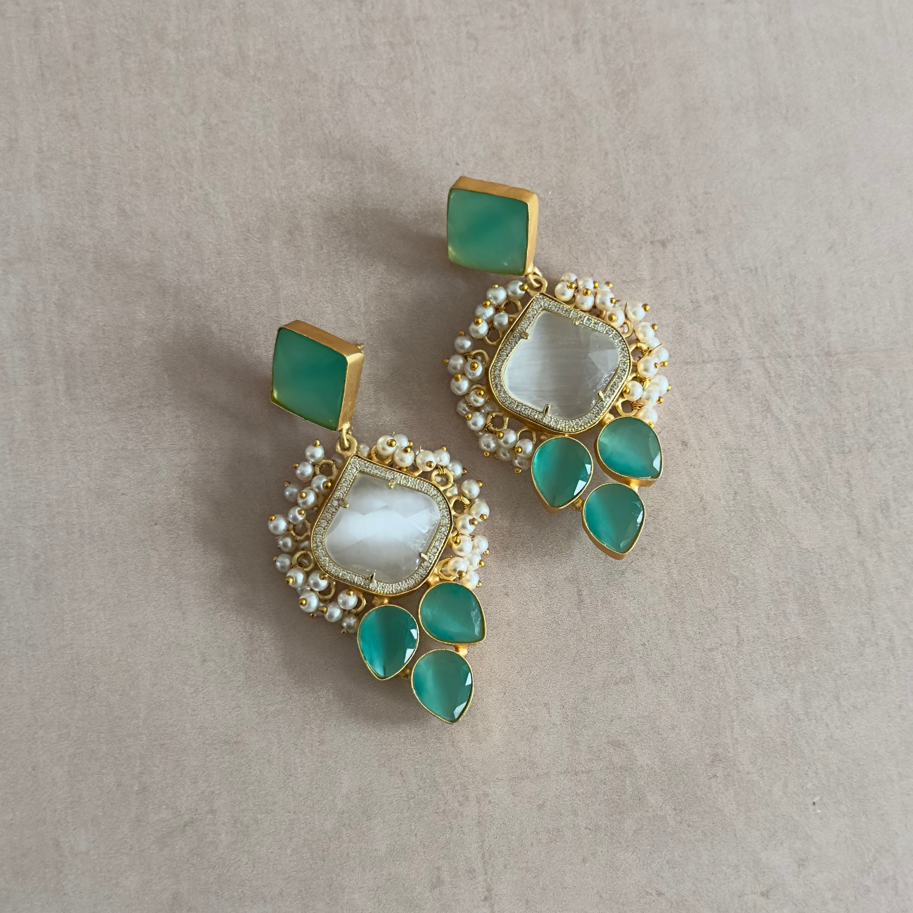 The Hijra Mint Earrings feature a stunning statement design that will be sure to turn heads. The vibrant mix of grey and mint adds a subtle yet eye-catching touch to any outfit. Elevate your style with these unique earrings!