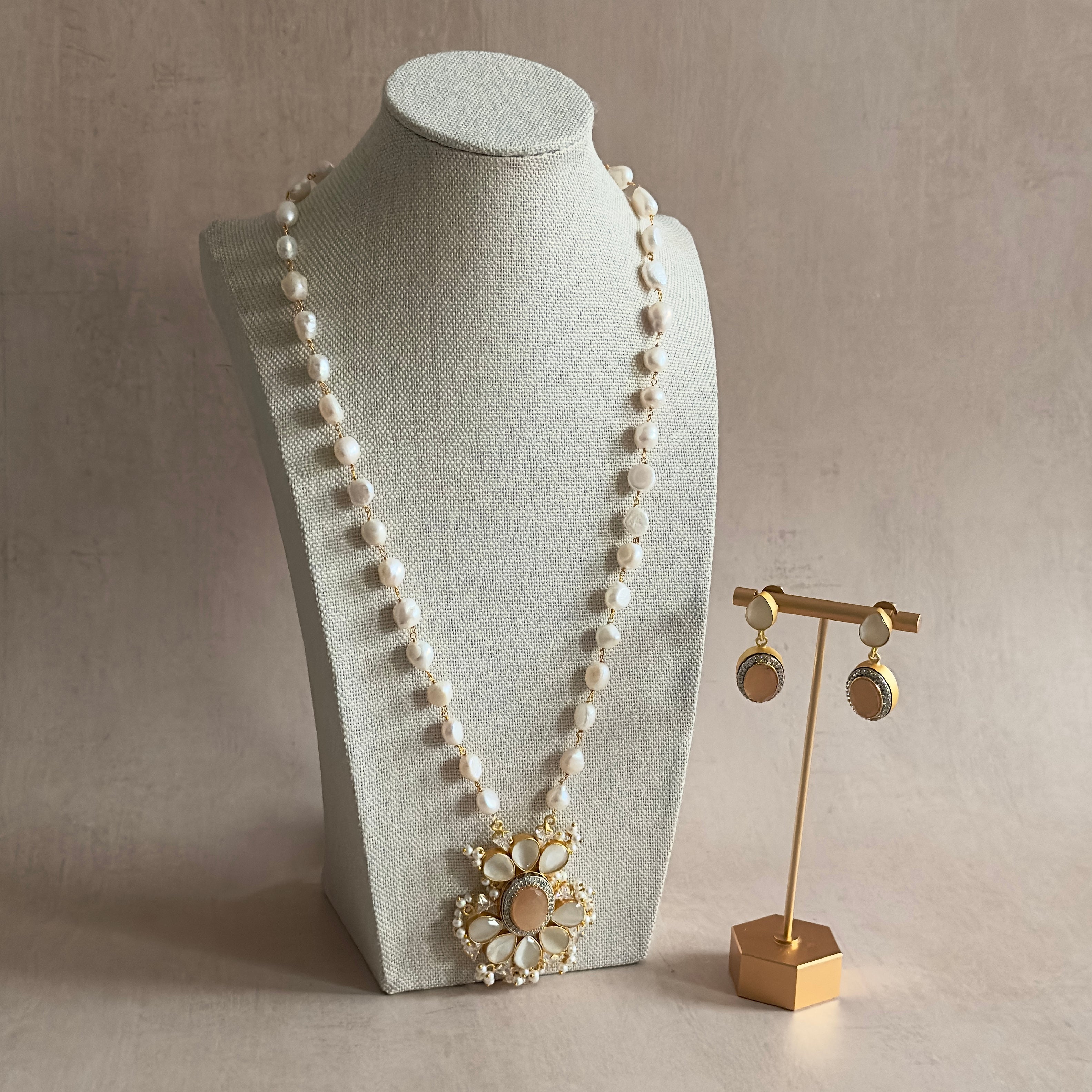 Elevate your look with our Jasmeen Grey Peach Mala Set! This stunning set features a long necklace design adorned with beautiful pearls with hues of peach and grey. Complete with the matching earrings for a sophisticated touch. Perfect for any occasion.