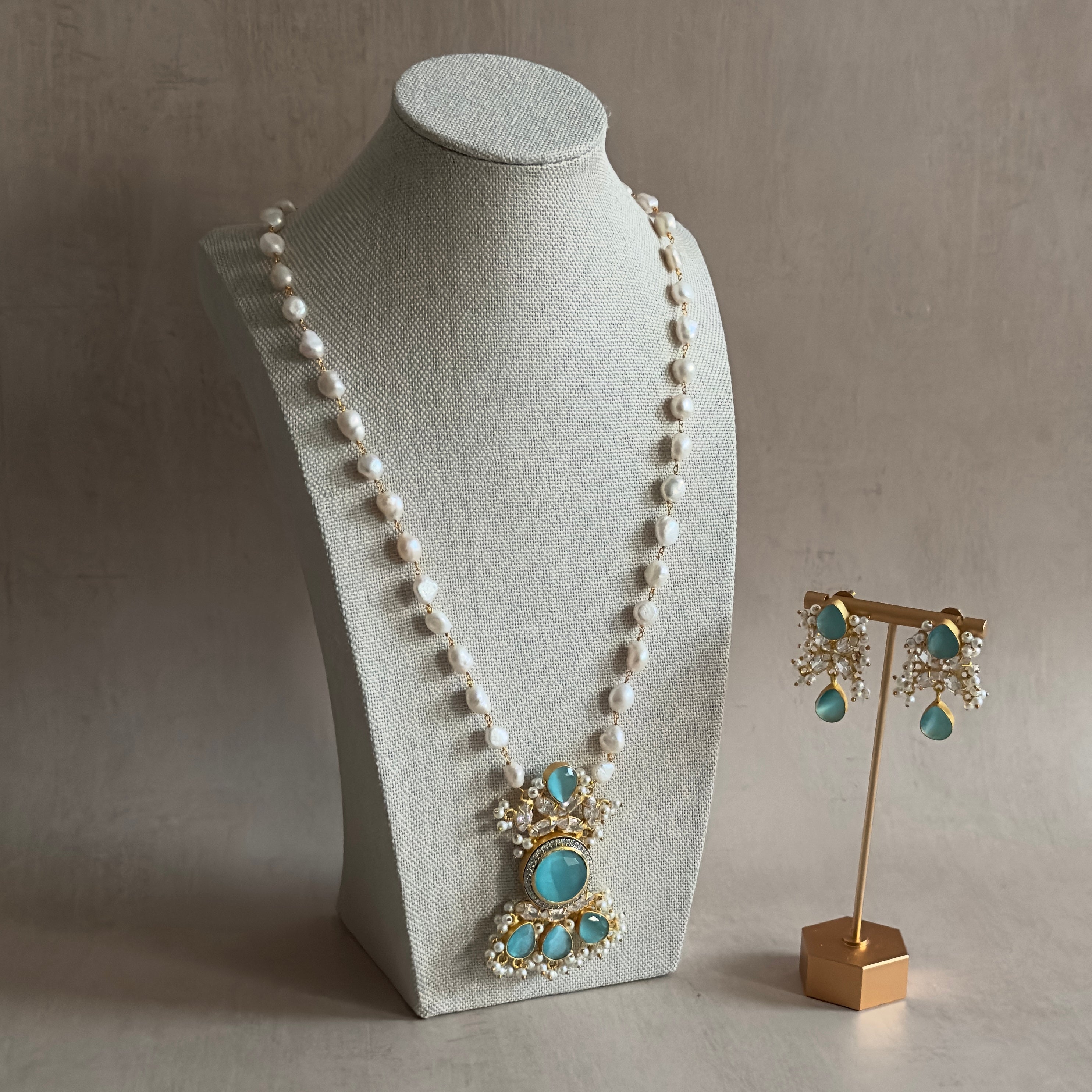 Elevate your style with our Amelia Blue Mala Set! This stunning long necklace set features aqua blue stones and sparkling cz crystals that will catch everyone's eye. Complete with matching earrings, this set is perfect for any occasion. Add a touch of elegance to your ensemble.