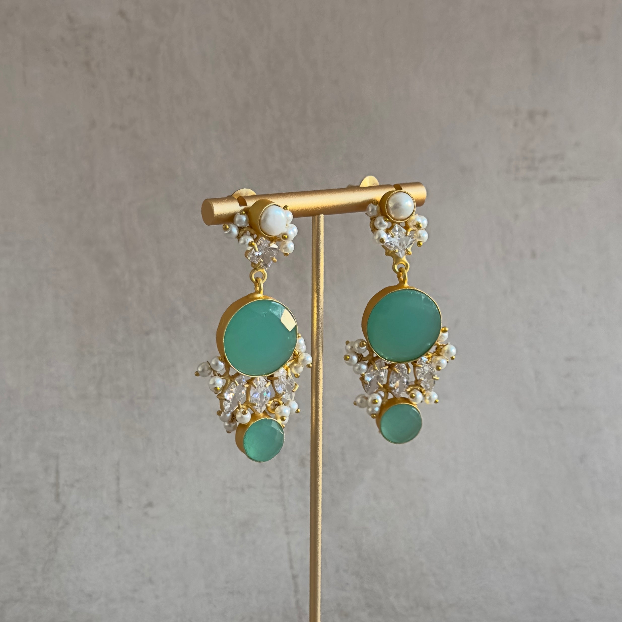Indulge in the stunning beauty of our Dina Earrings! The vibrant aqua green hue will add a pop of color to any outfit, while the delicate pearl accent and sparkling CZ crystals bring a touch of elegance. Elevate your style and turn heads with these must-have earrings!