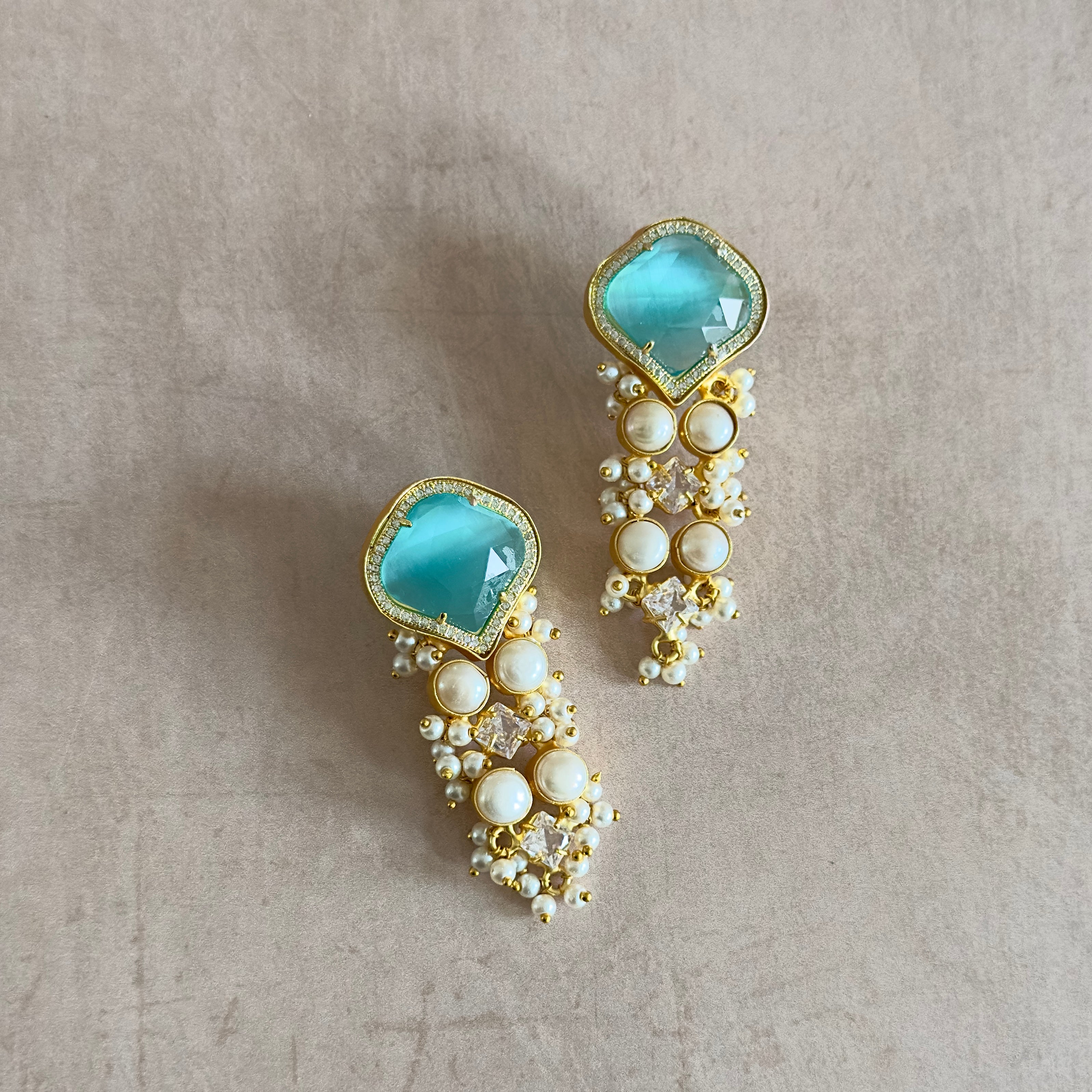 Experience the beauty and elegance of the Umaya Aqua Pearl Earrings. Adorned with vibrant aqua stones and freshwater pearls, and accented with sparkling crystals, these earrings exude a stunning design that will elevate any outfit. Bring a touch of sophistication to your style and make a statement with these exquisite earrings.