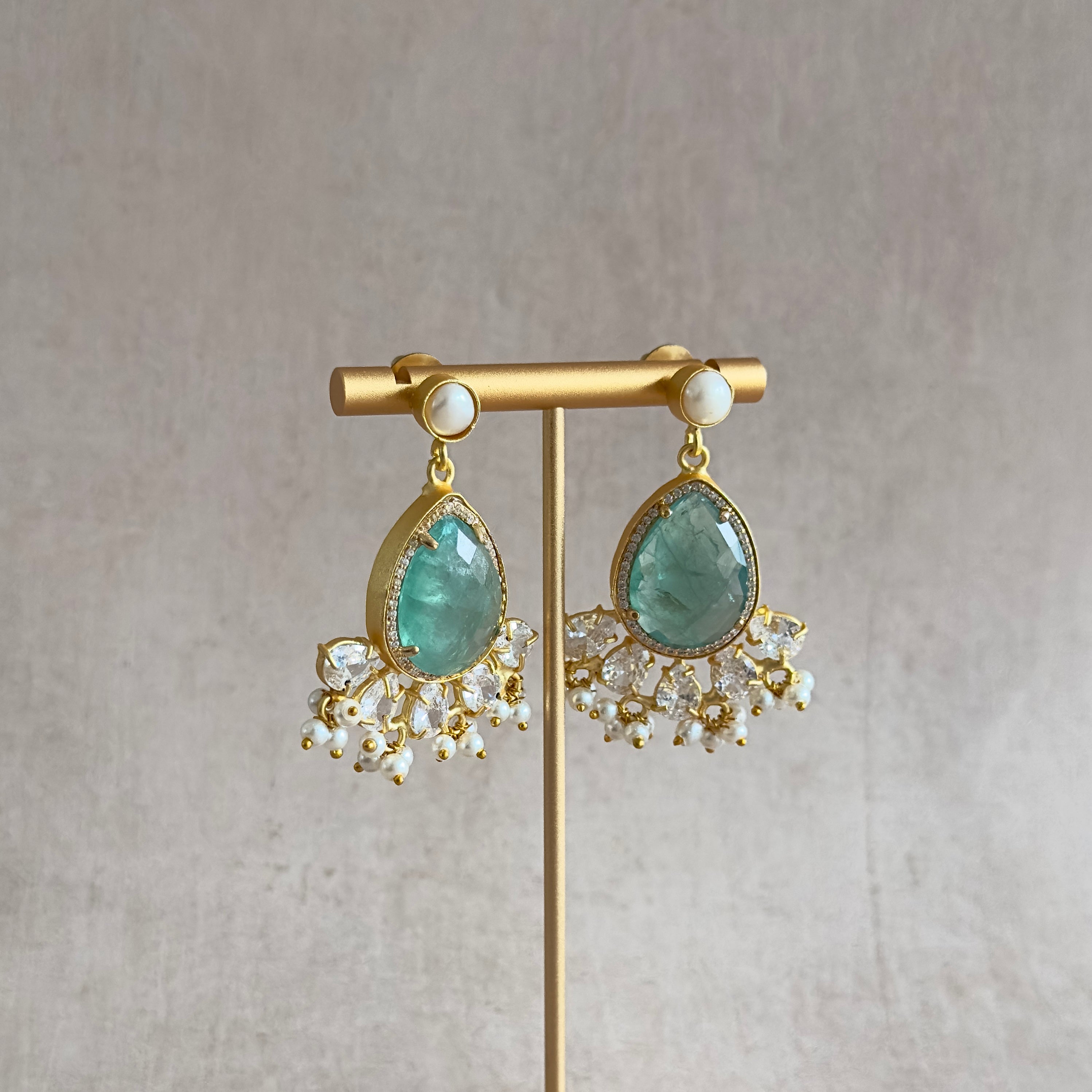 Indulge in the mesmerizing beauty of these Ciana Aqua Mint Pearl Drop Earrings. The stunning aquamarine crystals shimmer with elegance, while the pearl accent adds a touch of sophistication. Enhanced with sparkling cz crystals, these earrings will elevate any outfit with a touch of luxury.