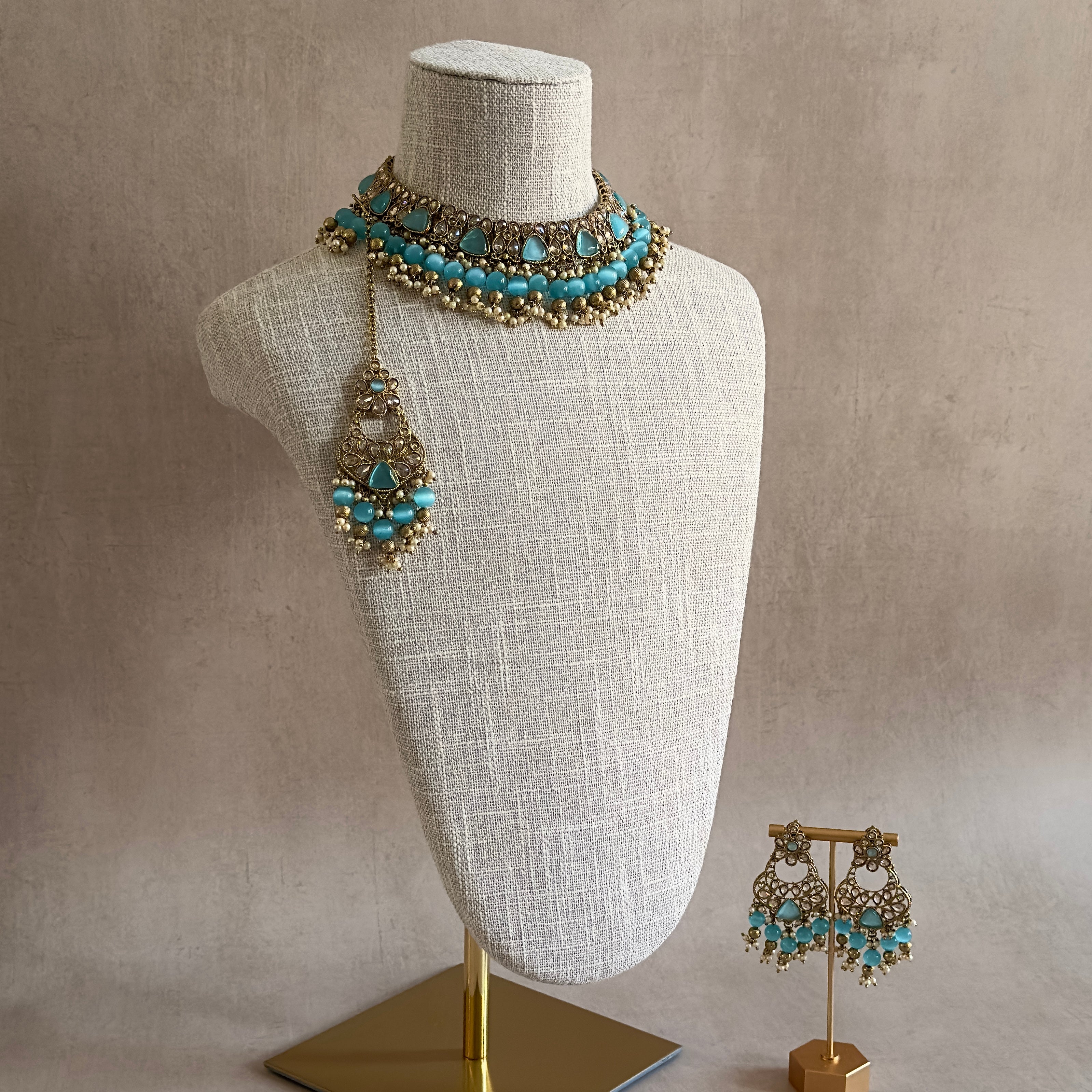 Elevate your accessories game with our Cassie Blue Choker Set. Featuring an antique gold finish and mesmerizing blue cateye stones, this set exudes sophistication. The adjustable fabric tie ensures a perfect fit, while the matching earrings and tikka complete the look. Make a luxurious statement with this must-have set.