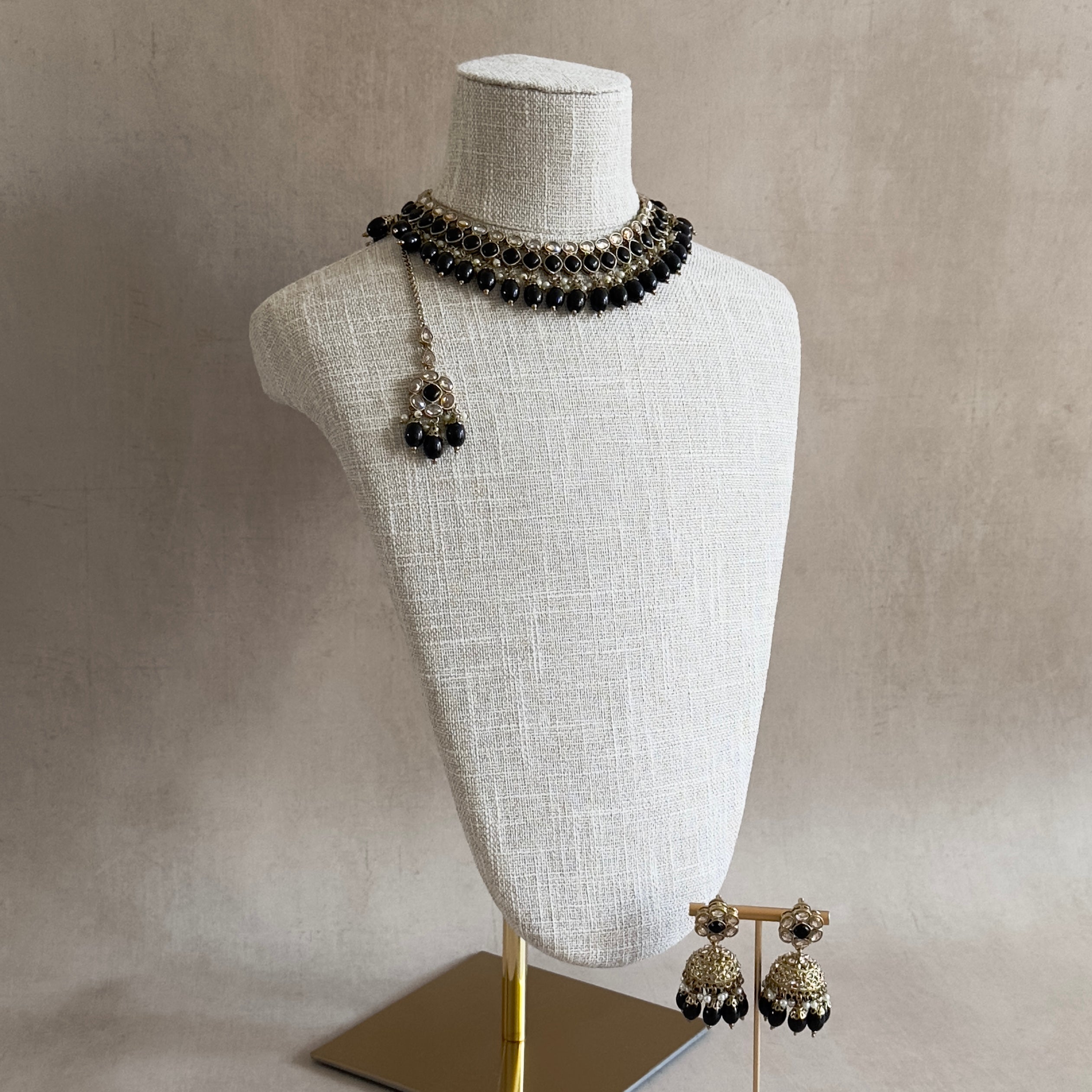 Elevate your outfit with our Keira Black Choker Set! This stunning set features Black Onyx beads in a elegant antique gold finish. The adjustable tie allows for the perfect fit, while the matching earrings and tikka complete the look.&nbsp;