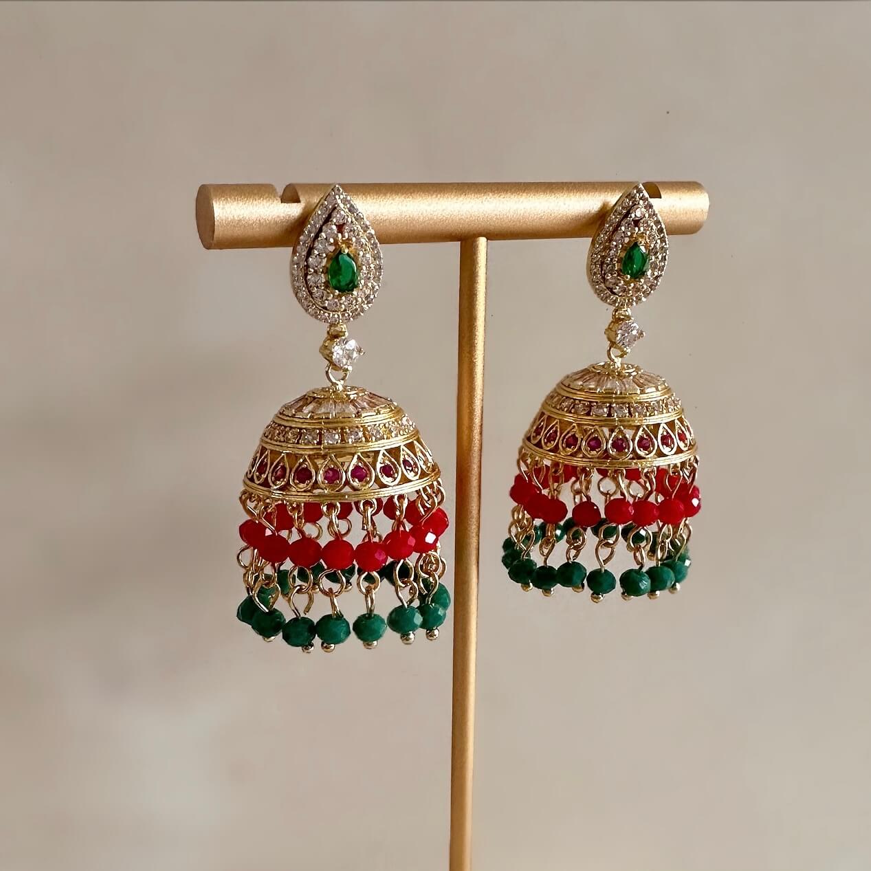 These Jhumki Earrings provide a timeless, traditional look with bright red and green hues. The intricate design is detailed with delicate crystal zirconia stones for subtle sparkle. Perfect for special occasions.