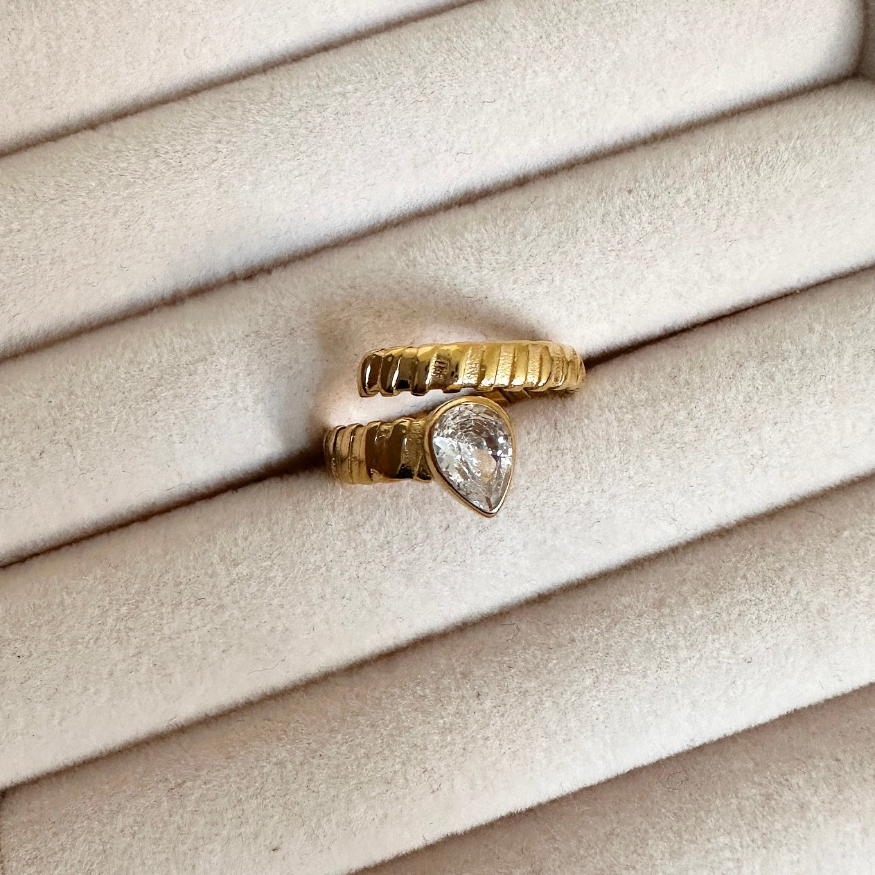 The Hold Me Tight Ring features an emerald / clear stone elegantly wrapped up in a simple and sophisticated design. Crafted with modern sophistication, this ring is sure to stand out.  18k gold plated ring. Details: Adjustable one size.